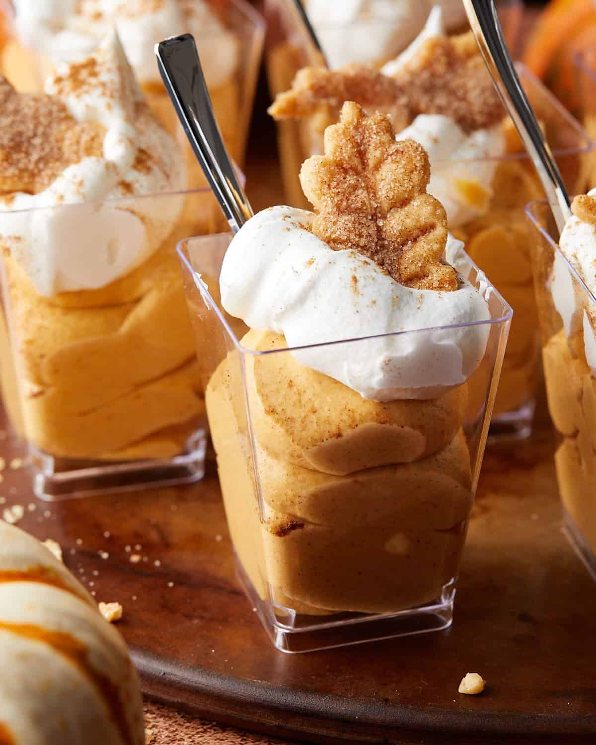 Up close image of creamy pumpkin pie in a cup layered with whipped topping and warm fall spices