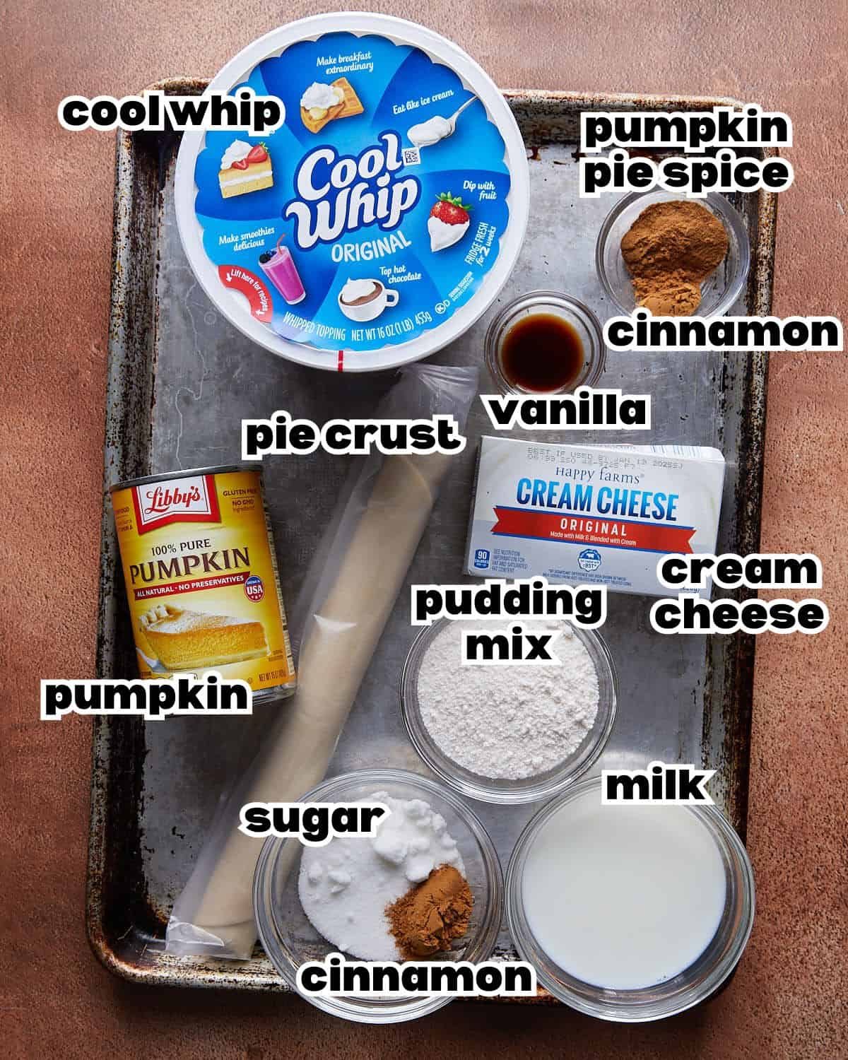 Overhead image of ingredients needed to make pumpkin pie in a cup, including pumpkin puree, whipped topping, pudding mix, spices, and pie crust arranged in bowls.