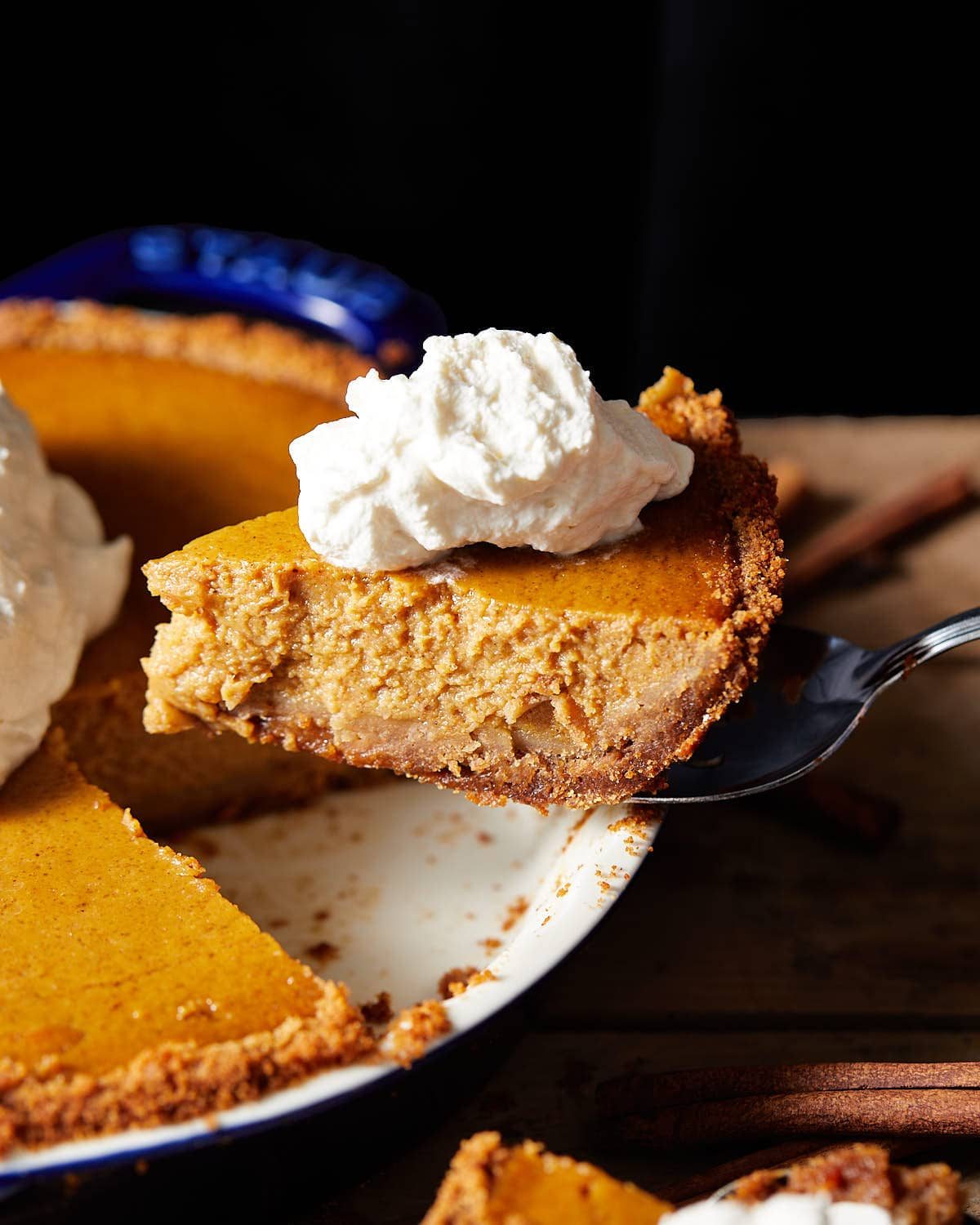 A slice of pie being removed from the dish with whipped cream.