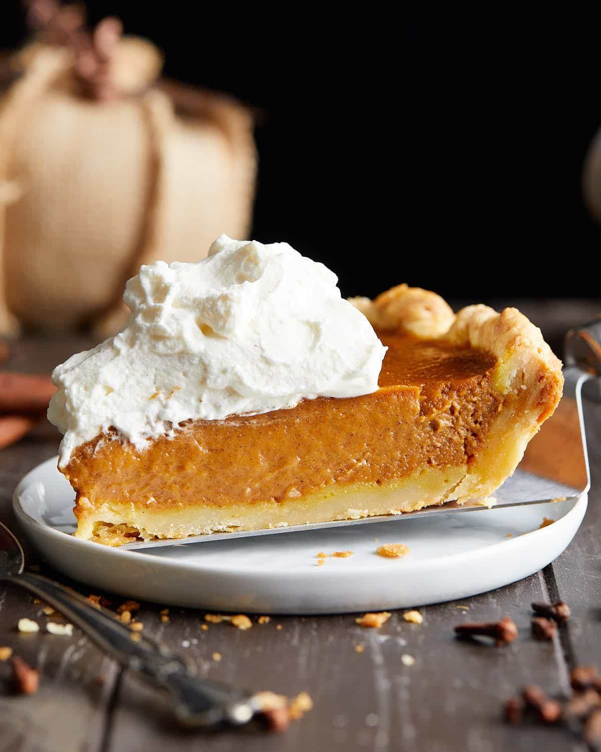 A side profile of pumpkin pie with whip cream topping.
