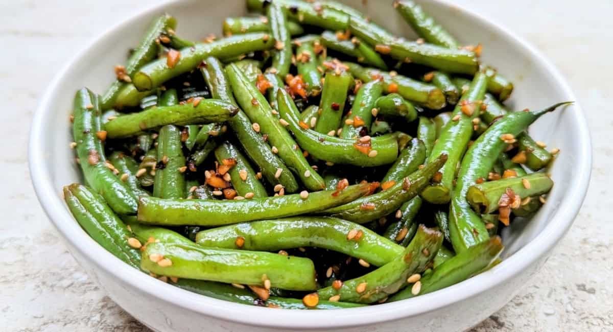 Overhead image of garlic sesame green beans in white bowl.