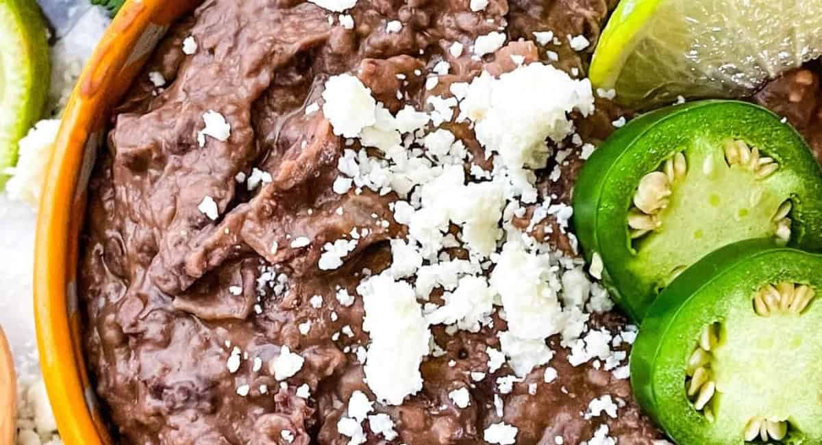 Overhead image of black refried black beans with garnish.