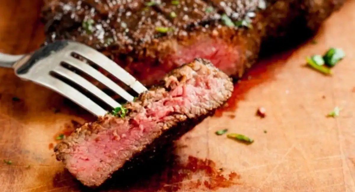 Up close image of marinated ribeye steaks with fork.
