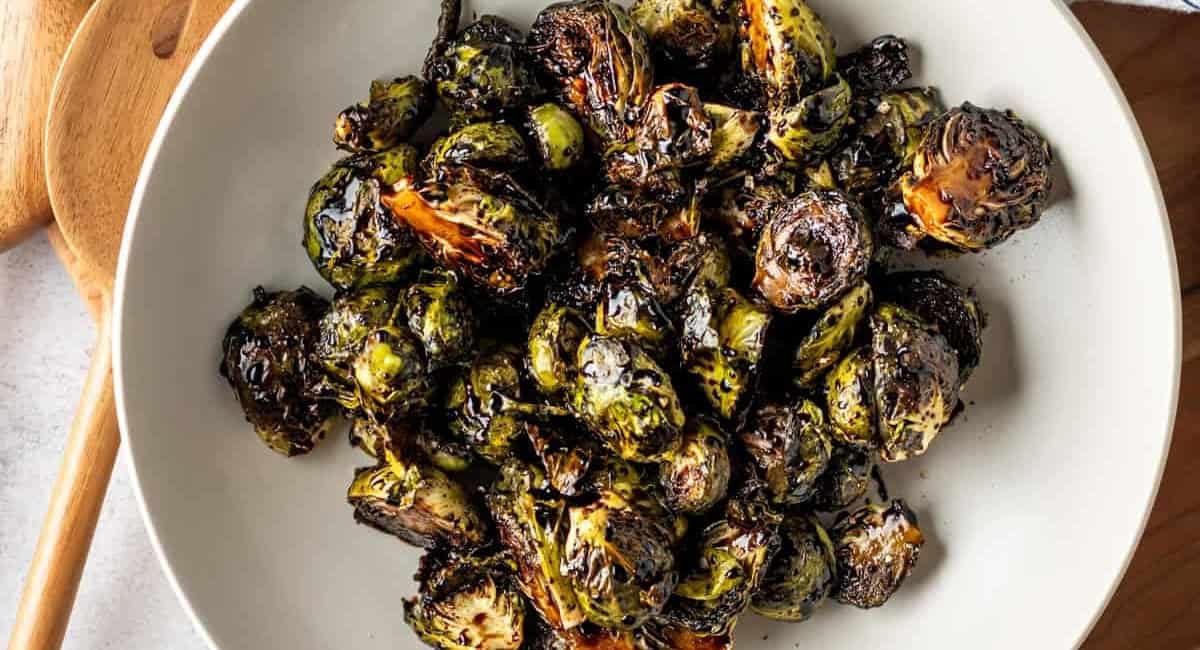 Overhead image of brussels sprouts with balsamic glaze in white bowl.