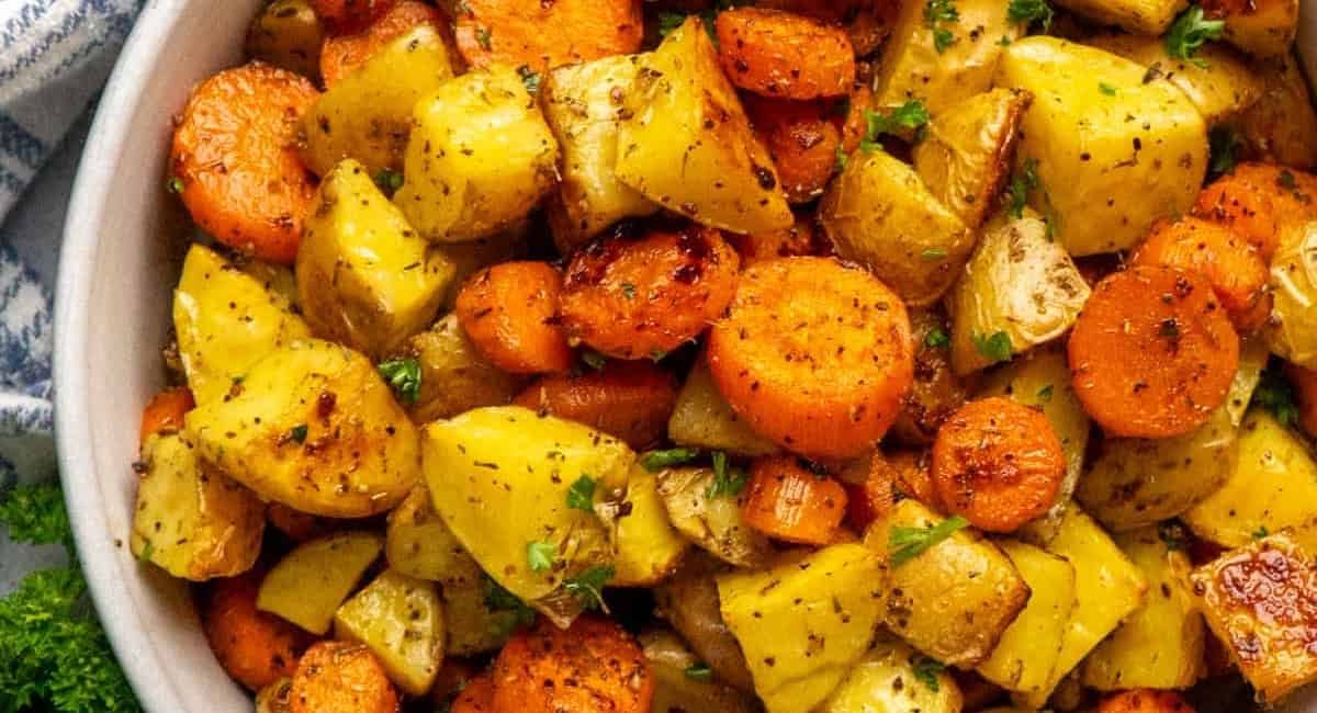 Overhead image of roasted potatoes and carrots with garnish.