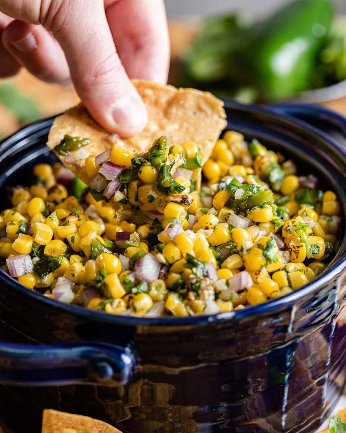 chip being dipped in roasted chili corn salsa