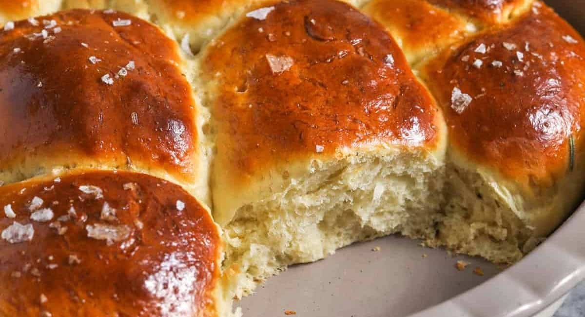 Up close image of herby garlic dinner rolls in white baking dish.