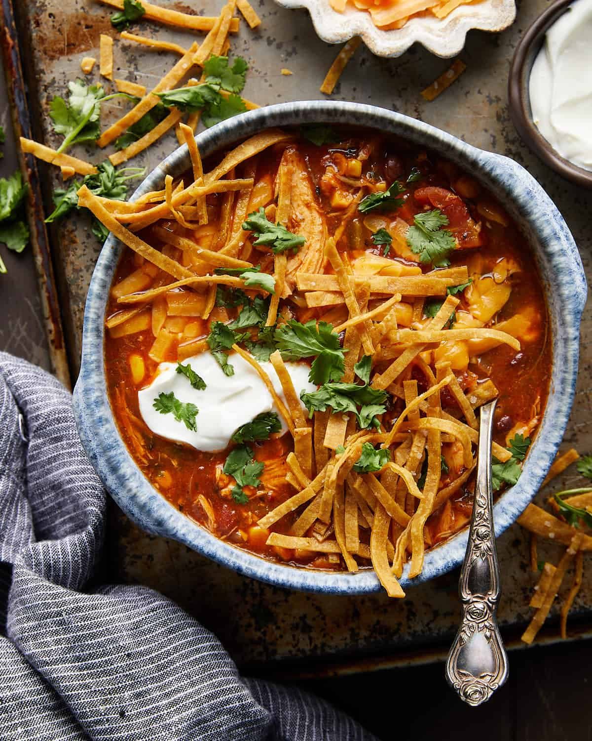 Overhead image of chicken tortilla soup with tortilla strips and garnish.