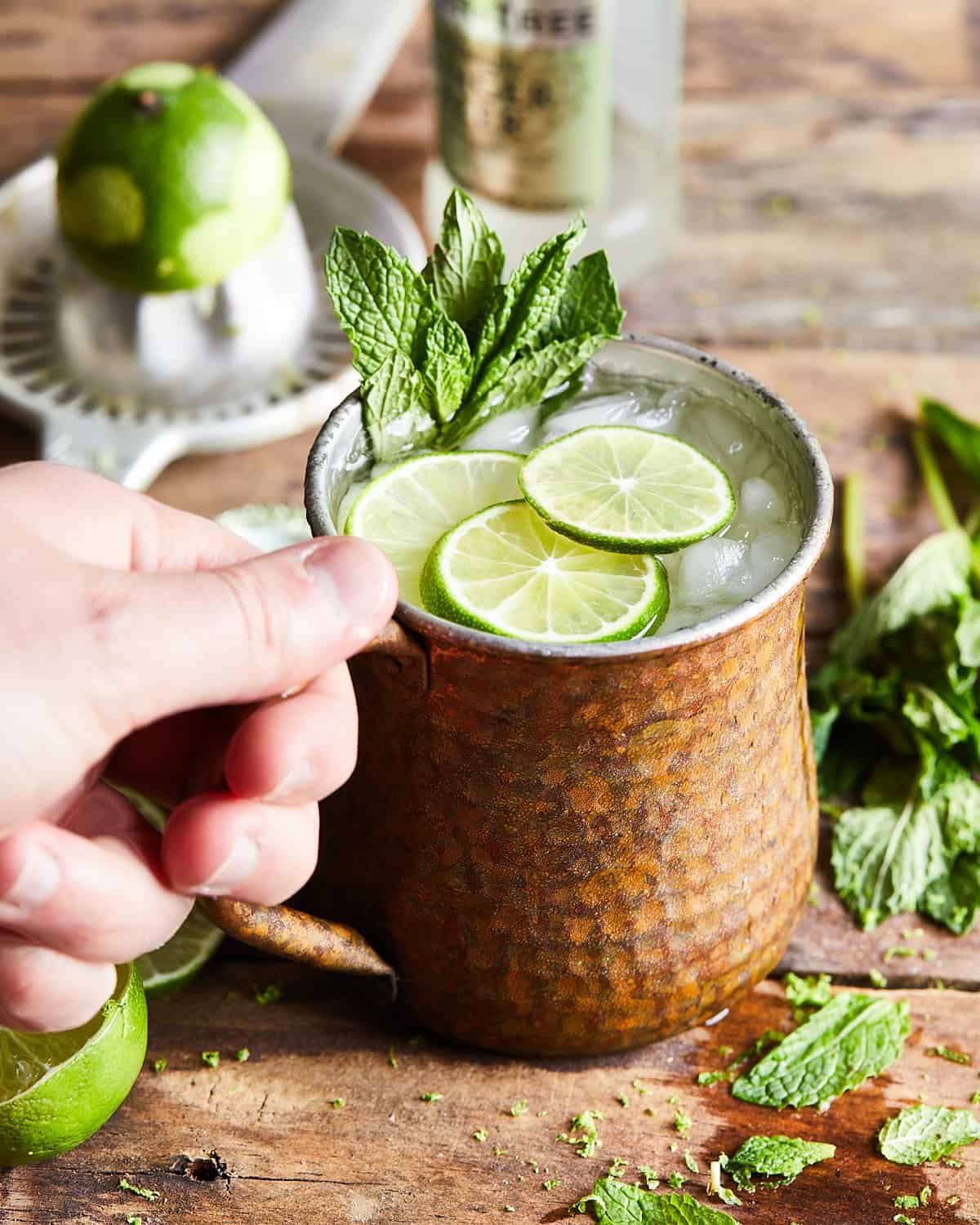 Hand grabbing rum moscow mule in a copper mug.