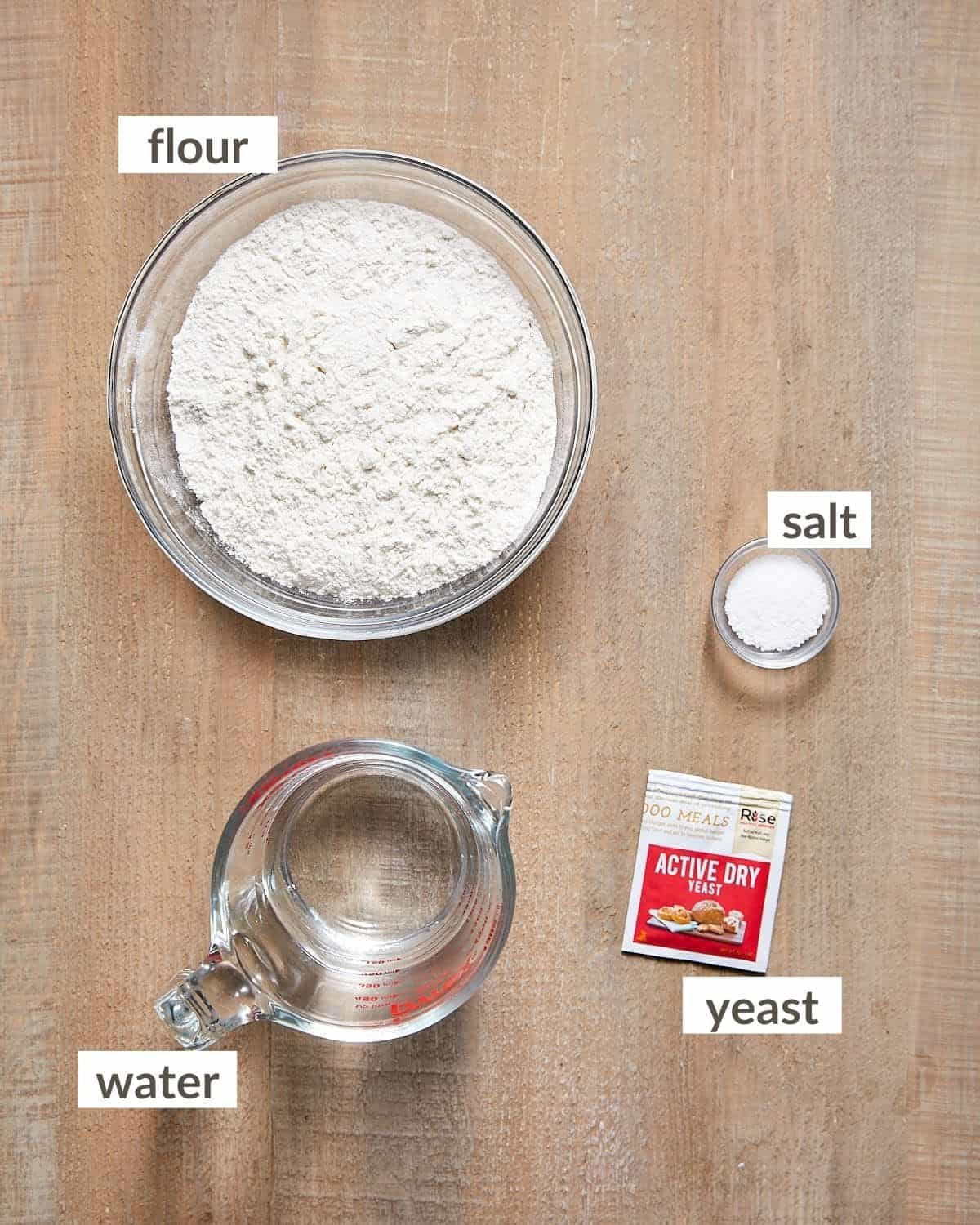 Bread flour, warm water, active dry yeast, and salt arranged in glass containers.