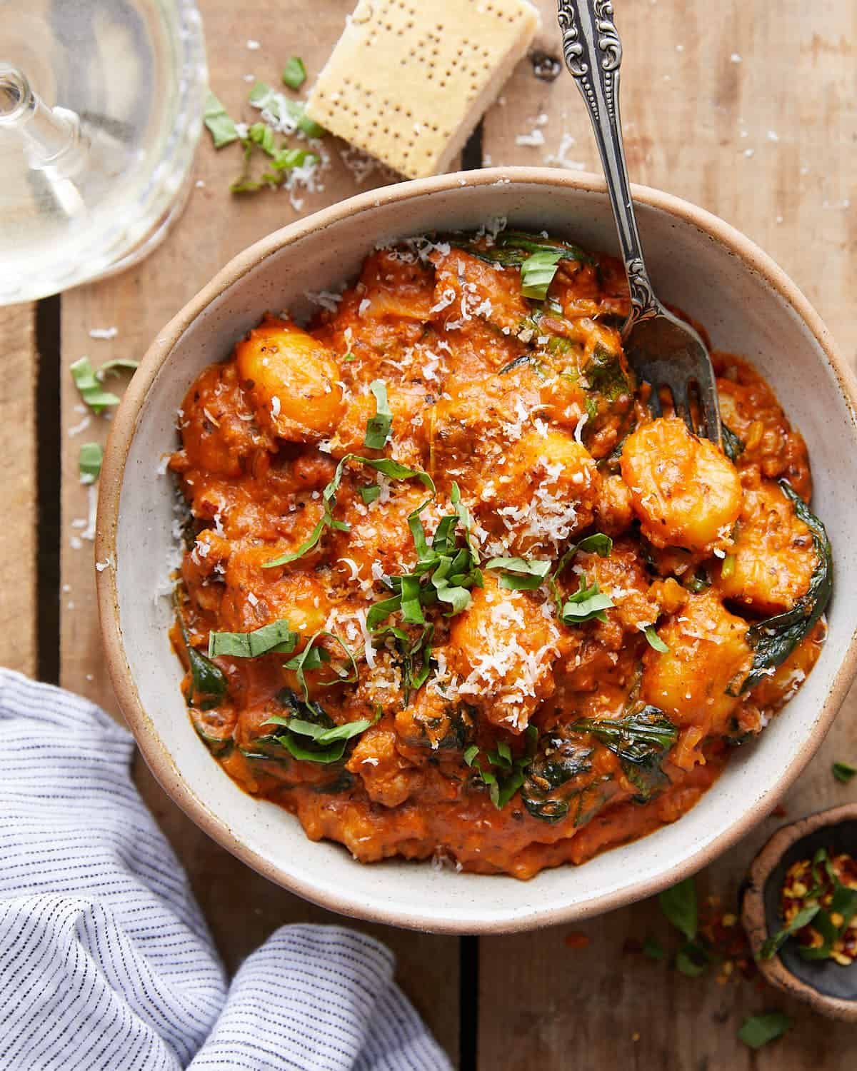 Overhead image of sausage gnocchi with tomato sauce and spinach.