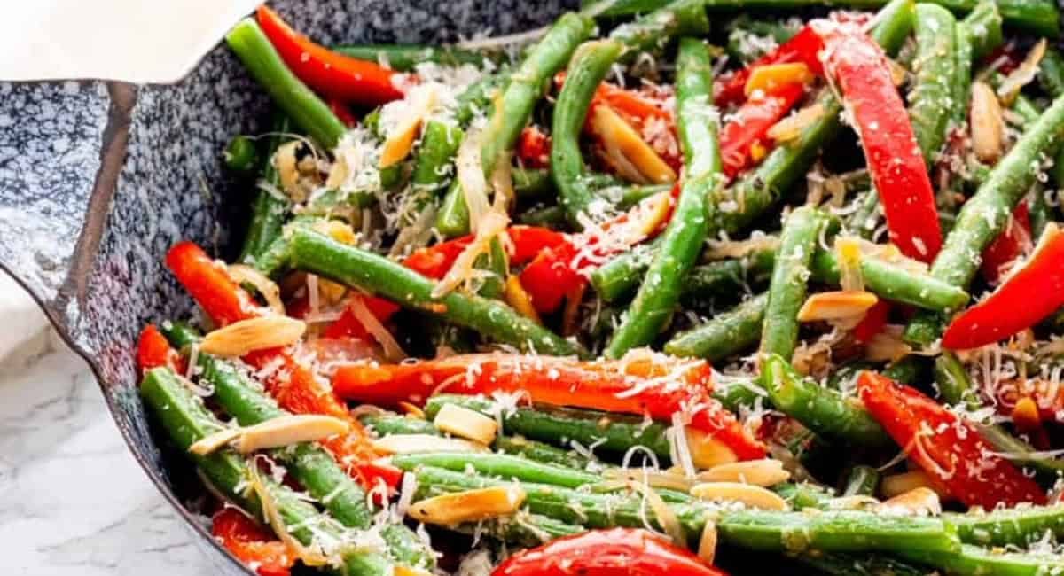 Overhead image of sautéed green beans with red peppers and almonds.