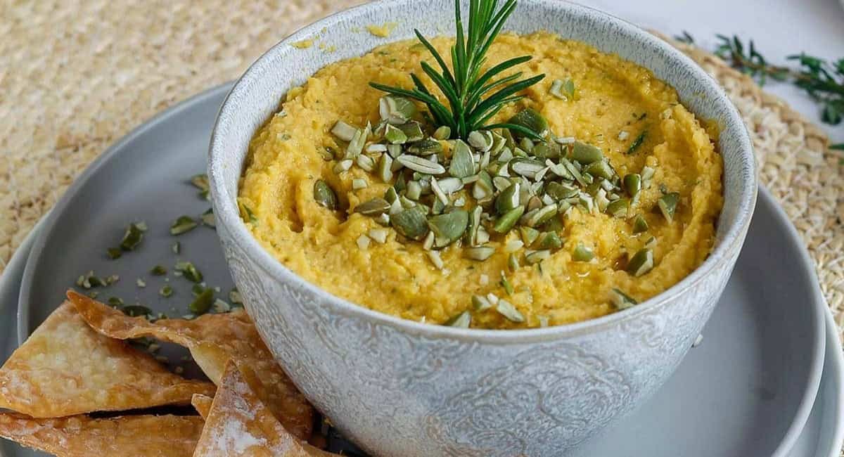 Up close image of savory pumpkin dip with garnish in small grey bowl.
