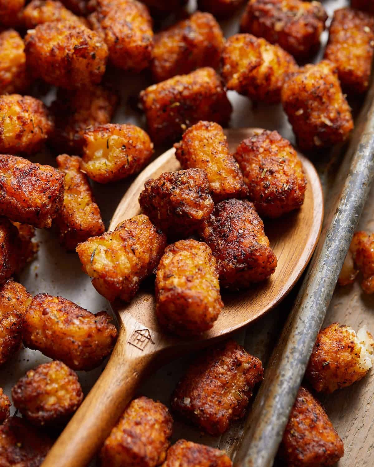 Seasoned tater tots on a wooden spoon.