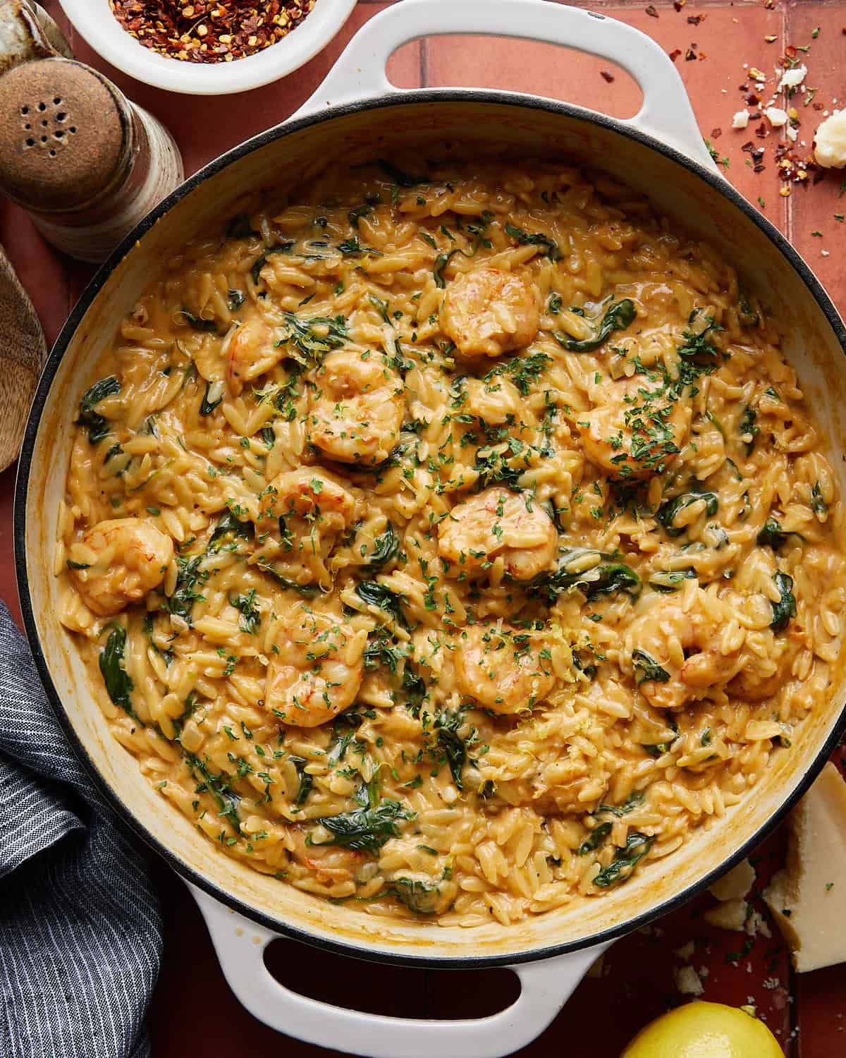 Overhead image of shrimp orzo in white skillet with garnish.