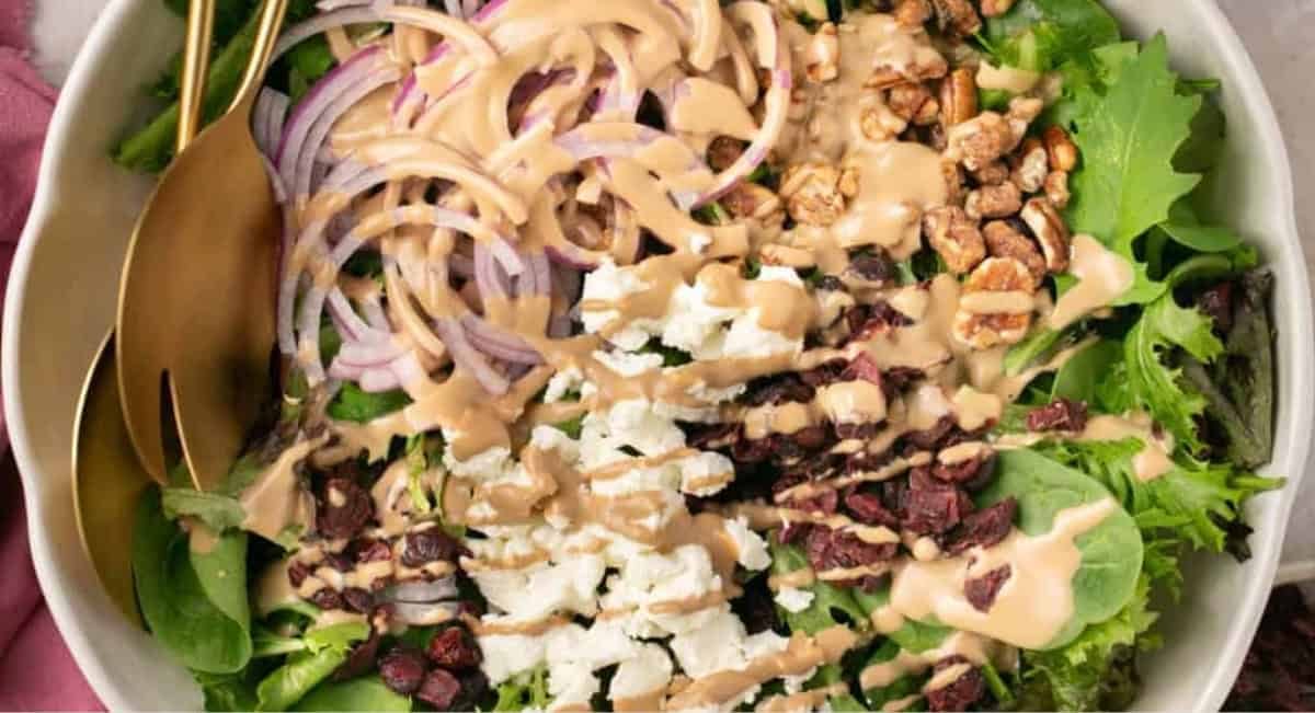 Overhead image of simple salad with goat cheese and cranberries with dressing.