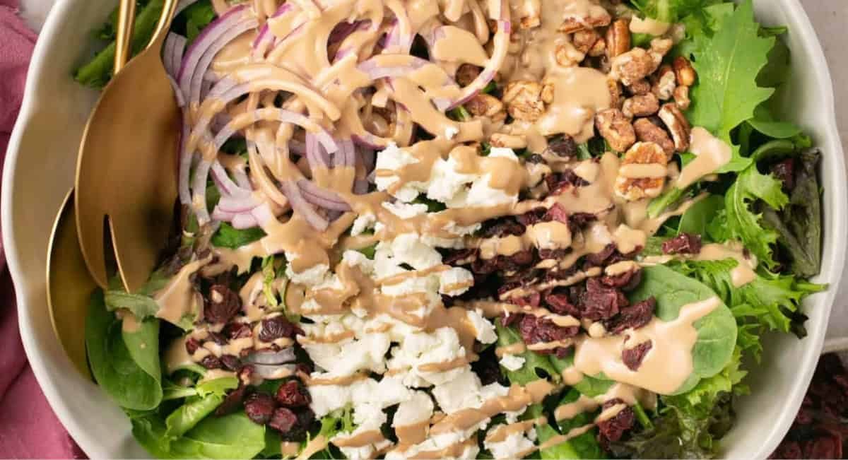Overhead image of simple salad with goat cheese and cranberries in a white bowl.
