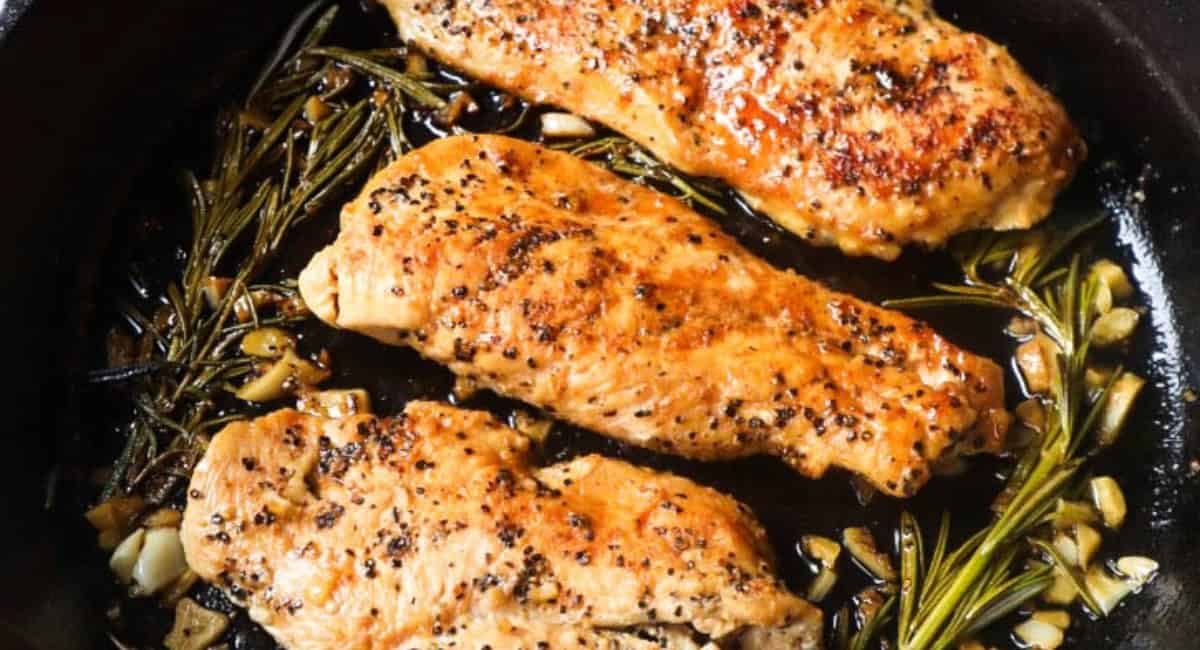 Overhead image of cast iron skillet chicken breast with garnish.