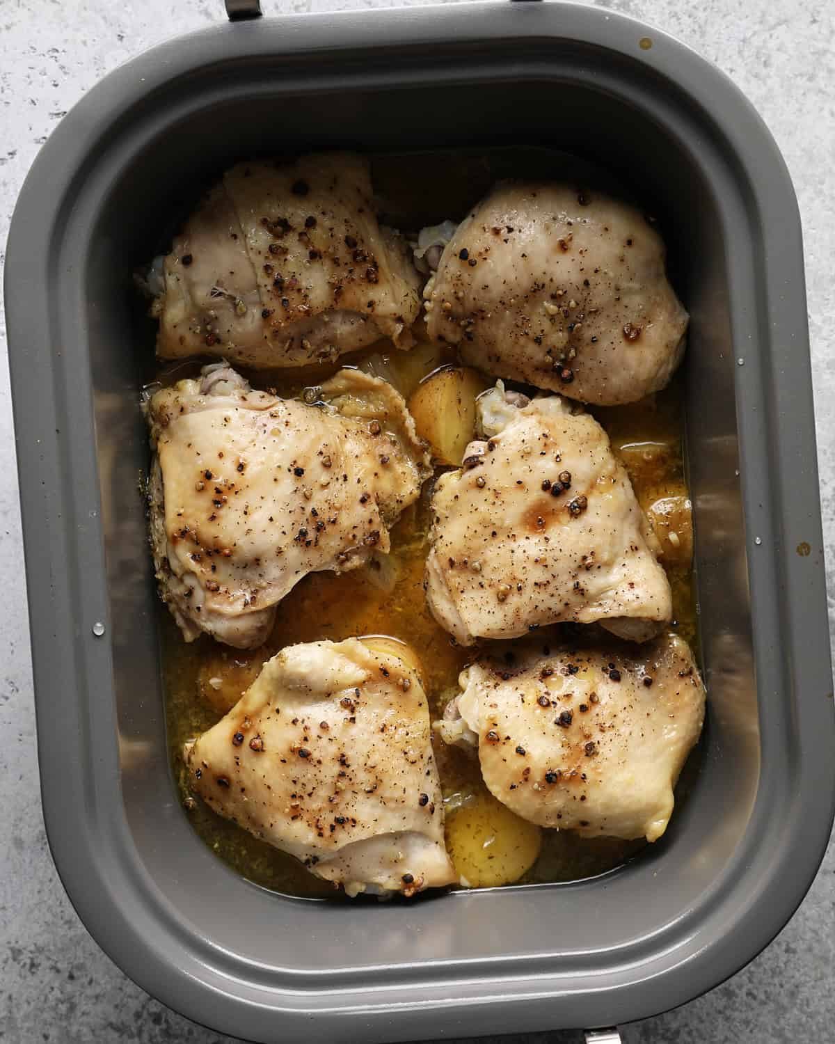 Cooked chicken thighs and fork-tender potatoes in a slow cooker.