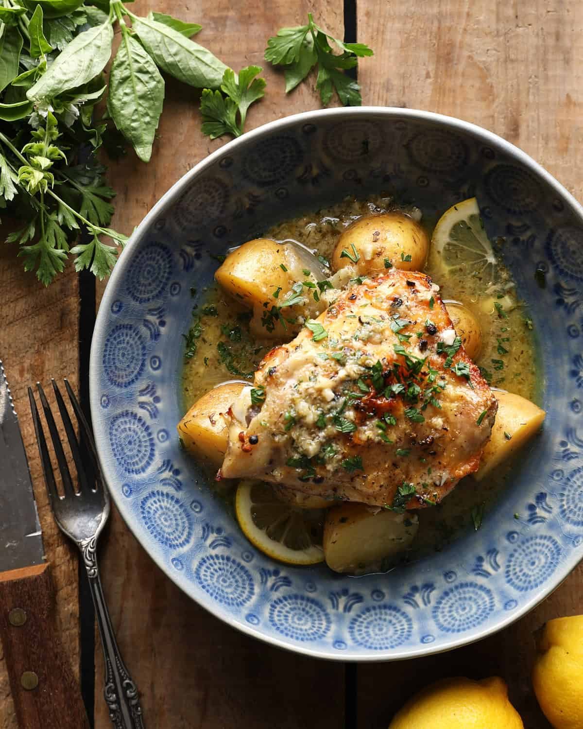 Greek lemon slow cooker chicken and potatoes with parsley in a blue bowl.
