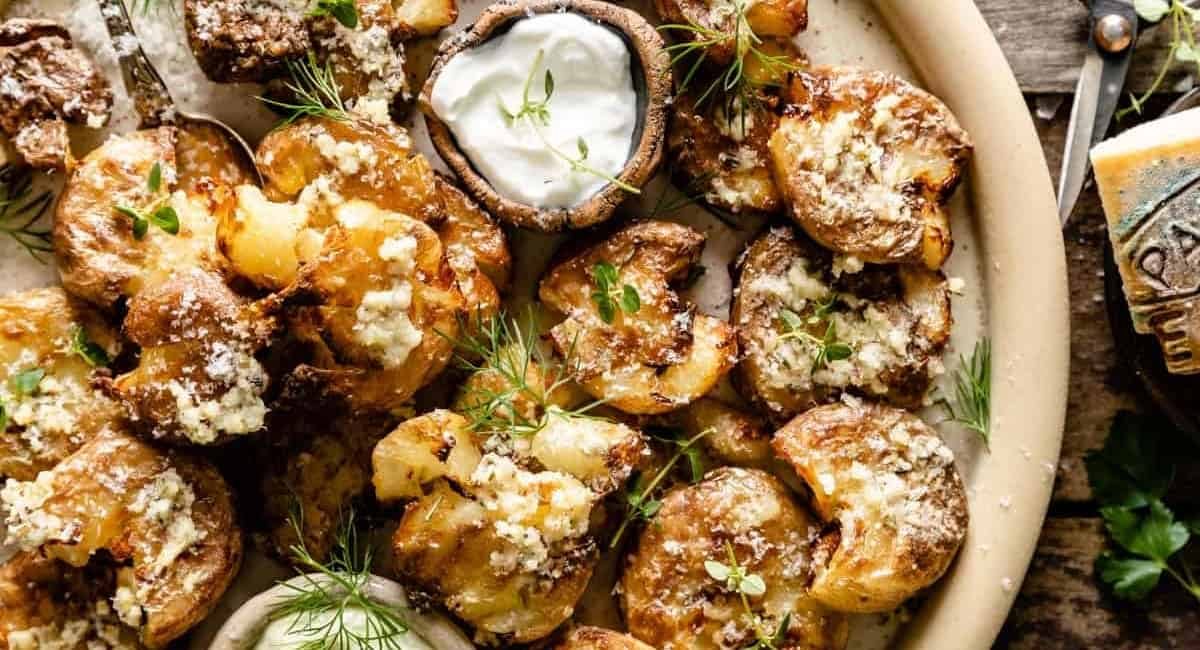 Overhead image of air fryer smashed potatoes with garnish.