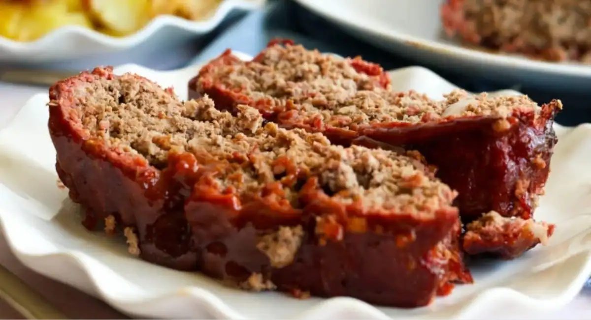 Up close side profile image of smoked meatloaf with sweet brown sugar glaze on white dish.