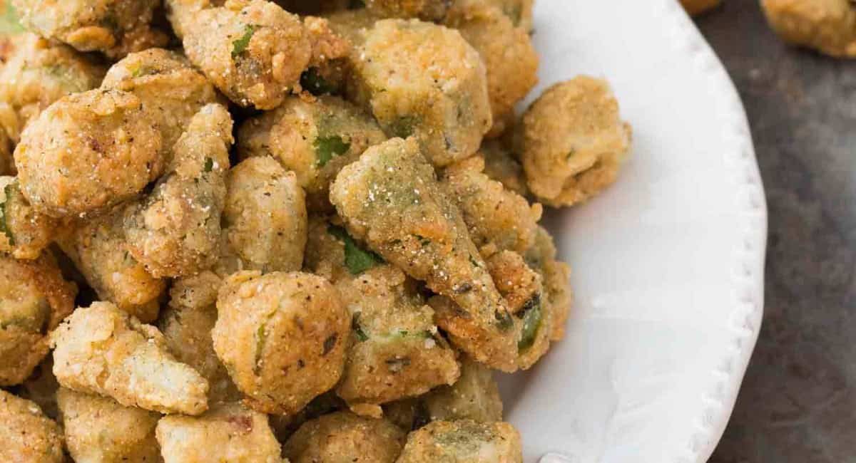 Up close image of southern fried okra with cornmeal on a white dish.