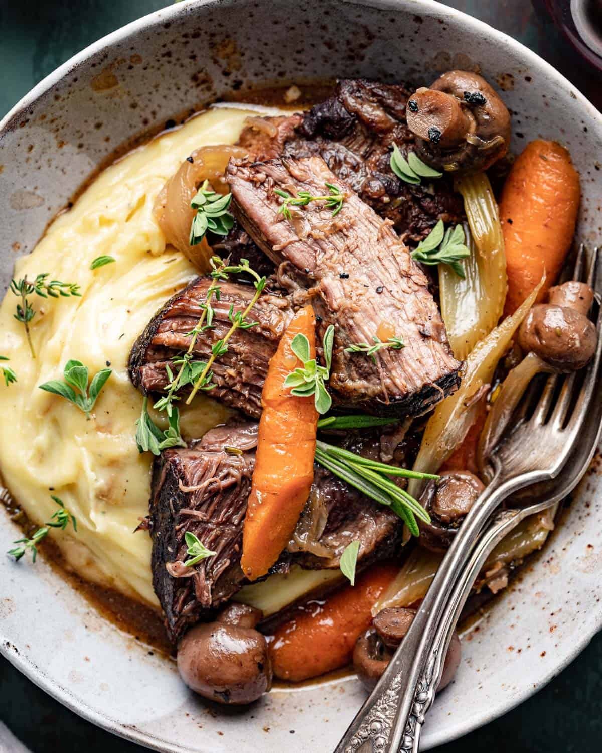 closeup of pot roast plated over mashed potatoes