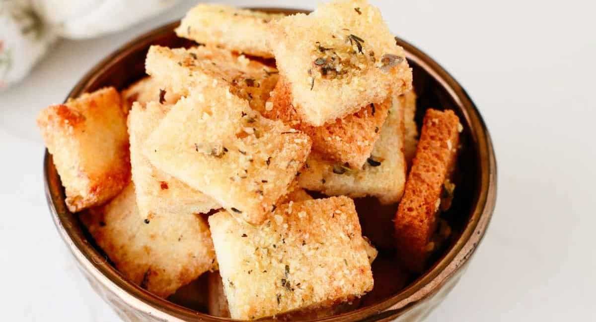 Up close image of parmesan croutons in brown bowl.