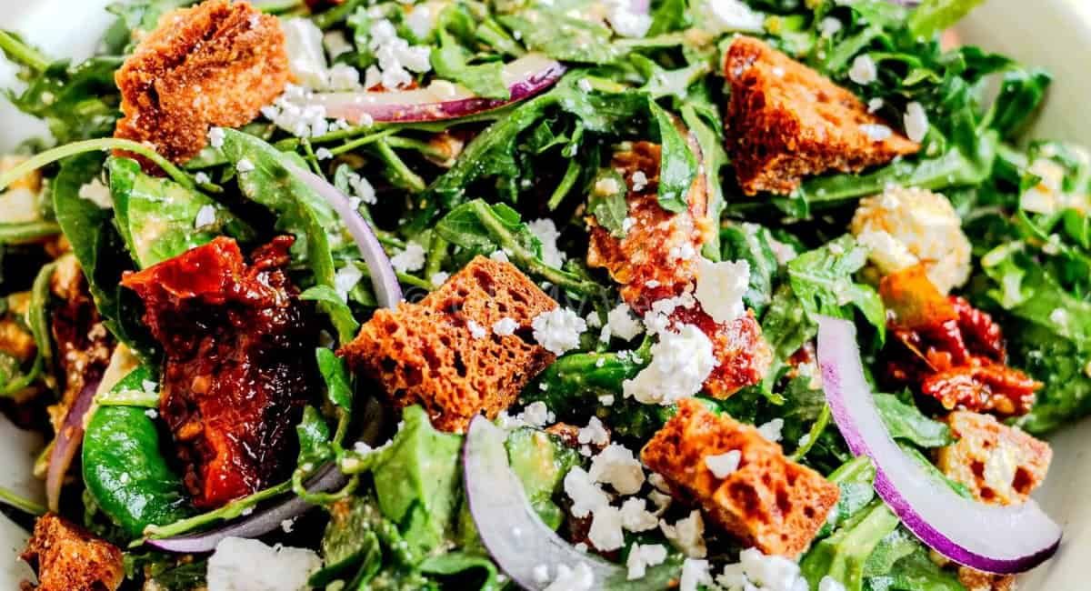 Overhead image of spinach and arugula salad with garnish.