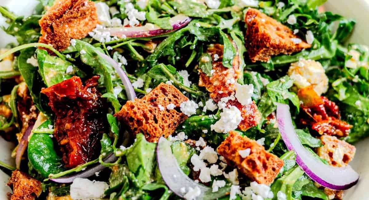 Up close overhead image of spinach and arugula salad with garnish.