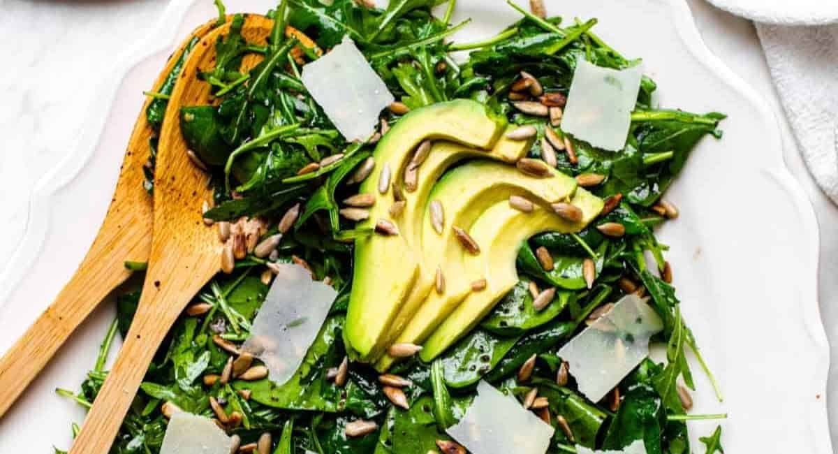 Overhead image of arugula spinach salad with garnish.