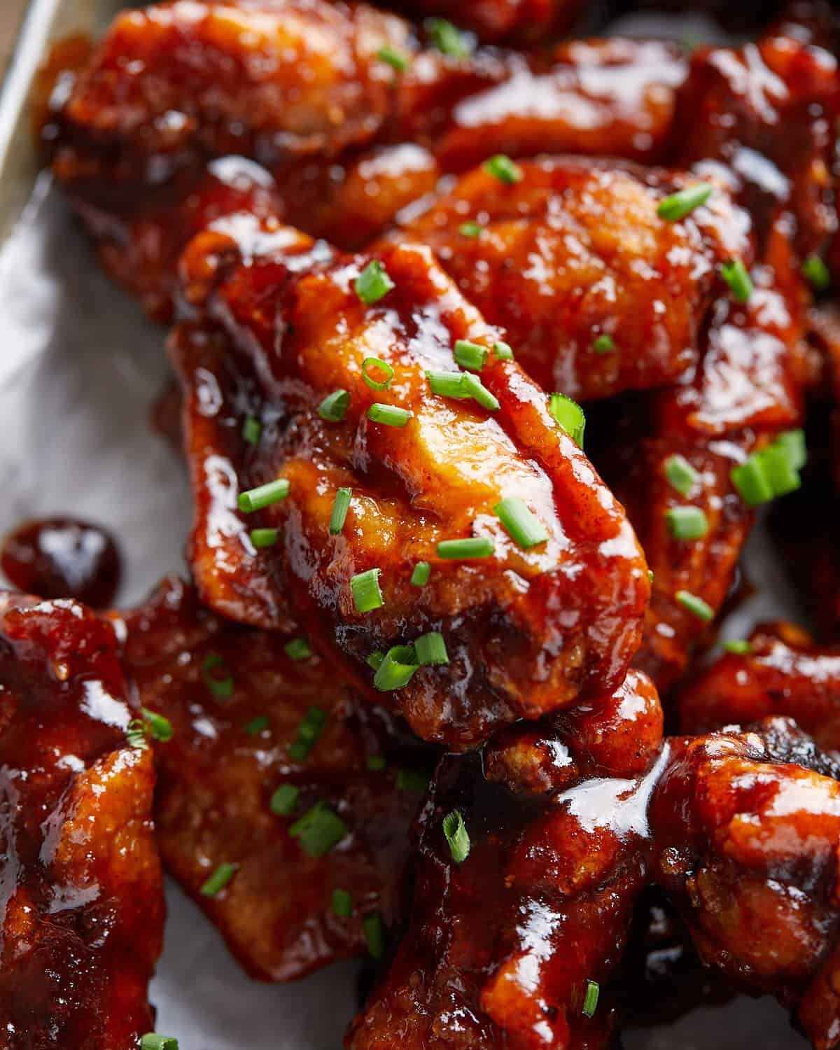 Up close image of sticky bbq chicken wings with garnish.