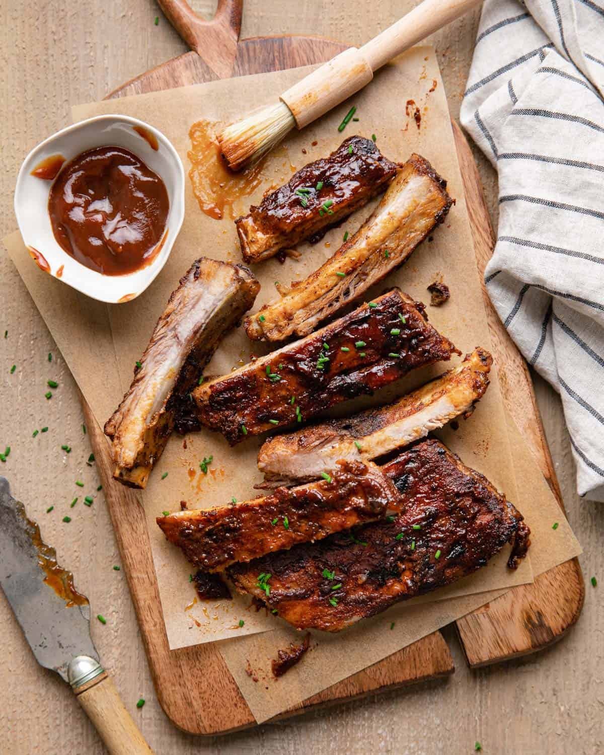 St louis rubs in oven on a cutting board with sauce on top.