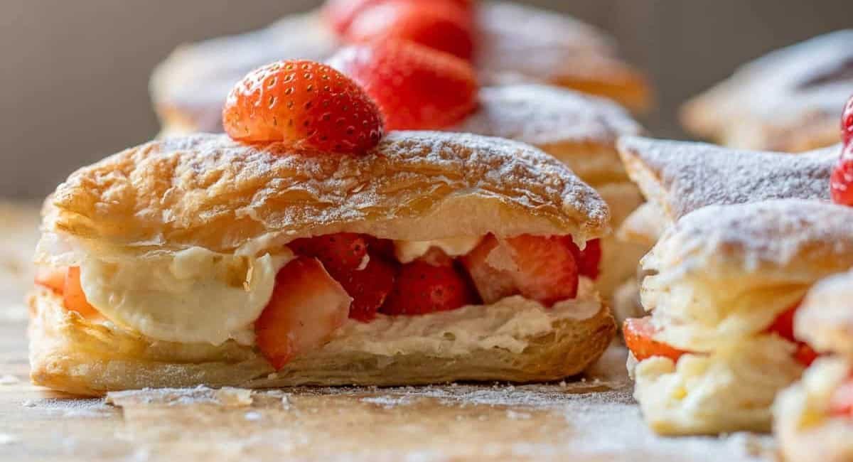 Side profile image of strawberry puff pastry stacks with cream.