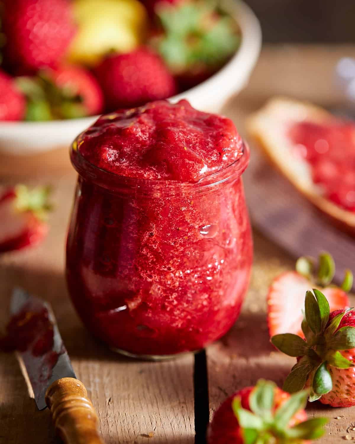 Up close image of strawberry jam preserves in glass container.