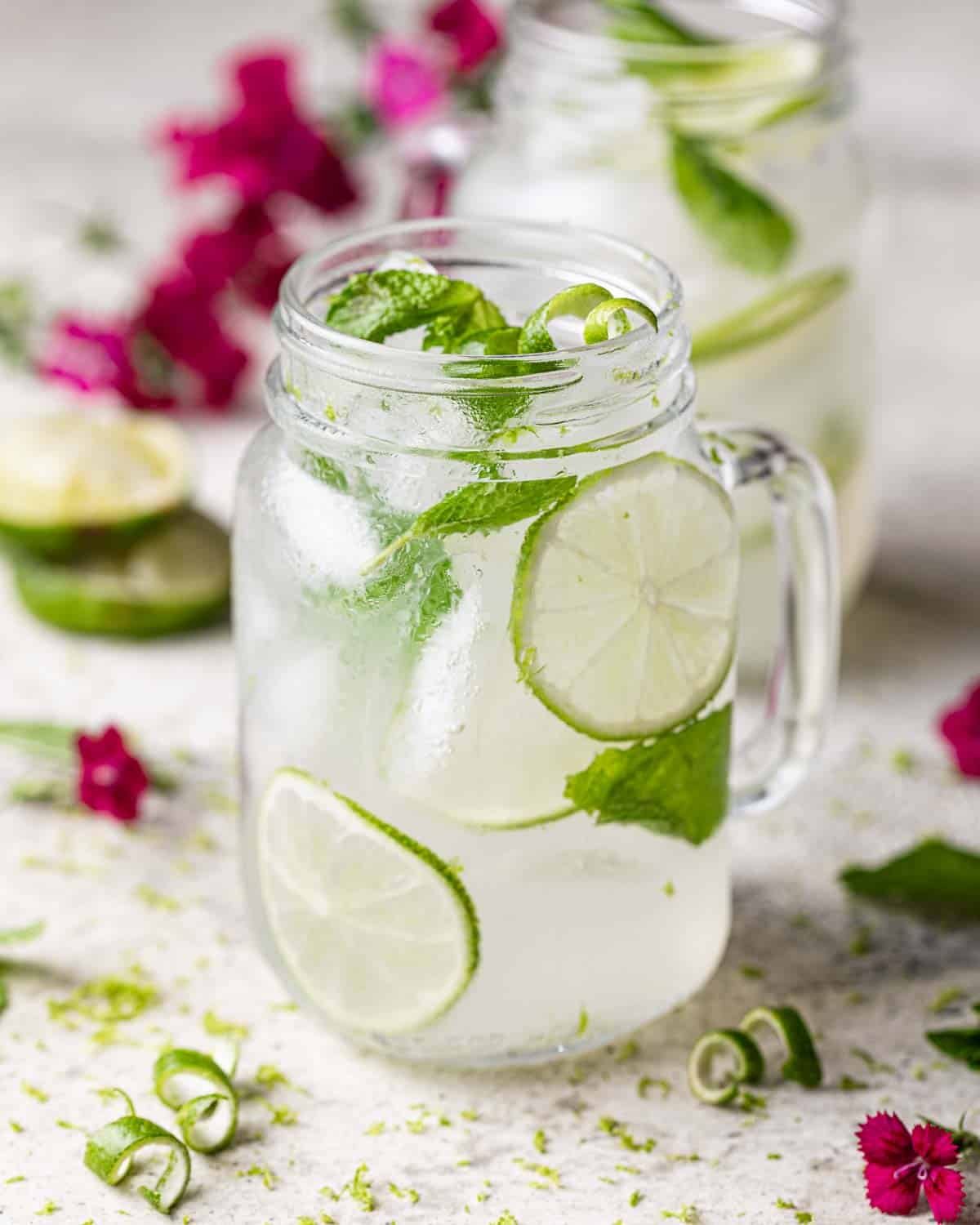 A tequila mule or mexican mule in mason jar glass garnished with limes and mint leaves.