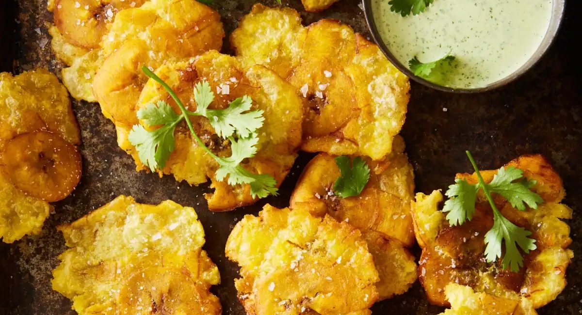Overhead up close image of tostones with cilantro jalapeno green sauce.