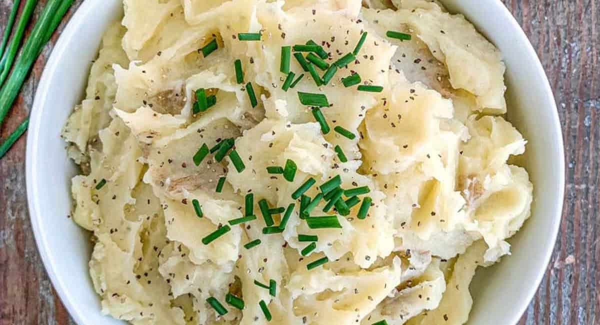 Overhead image of truffle mashed potatoes with garnish in a white dish.