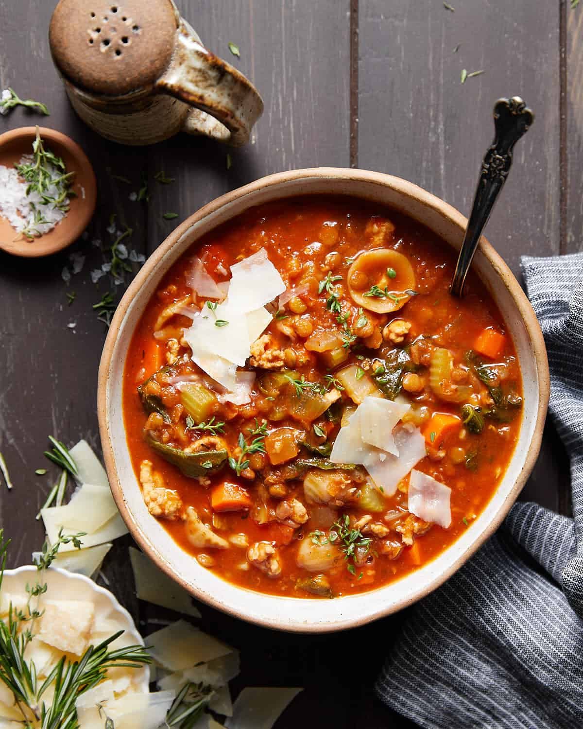 Turkey lentil soup in a white bowl with parmesan cheese on top.