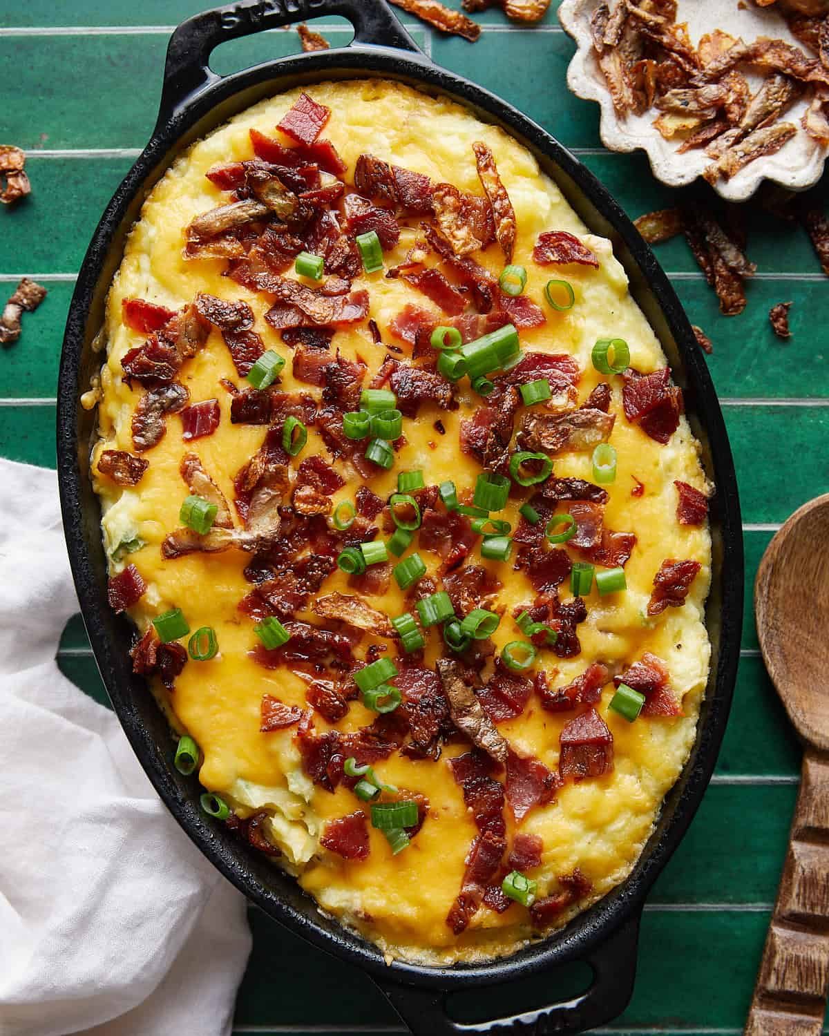 Overhead image of twice-baked mashed potatoes with bacon, green onions, crispy potato peel and cheese topping.