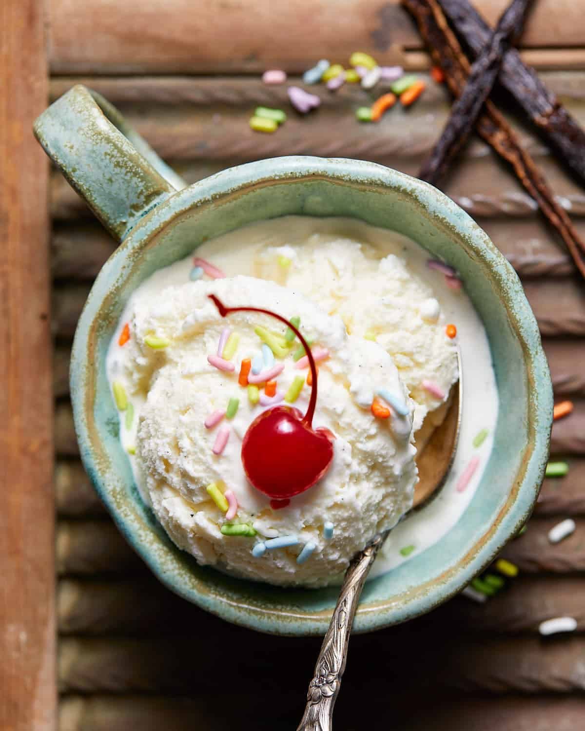 No egg vanilla ice cream in a mug with sprinkled and a cherry.