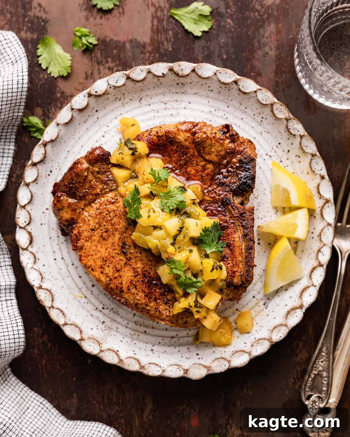 Perfectly cooked air fryer bone-in pork chop with warm apple and peach salsa on top, served on a plate.