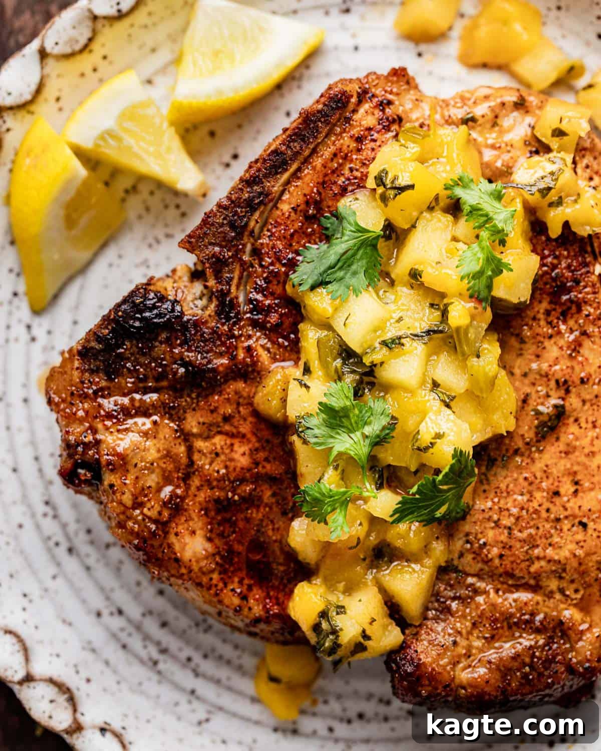 Close-up of a tender air fryer pork chop topped with a generous spoonful of warm apple and peach salsa, ready to be enjoyed.