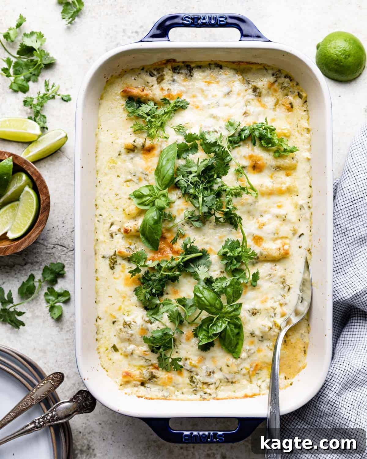 Green chili beef enchiladas with white sauce in a blue casserole dish. 
