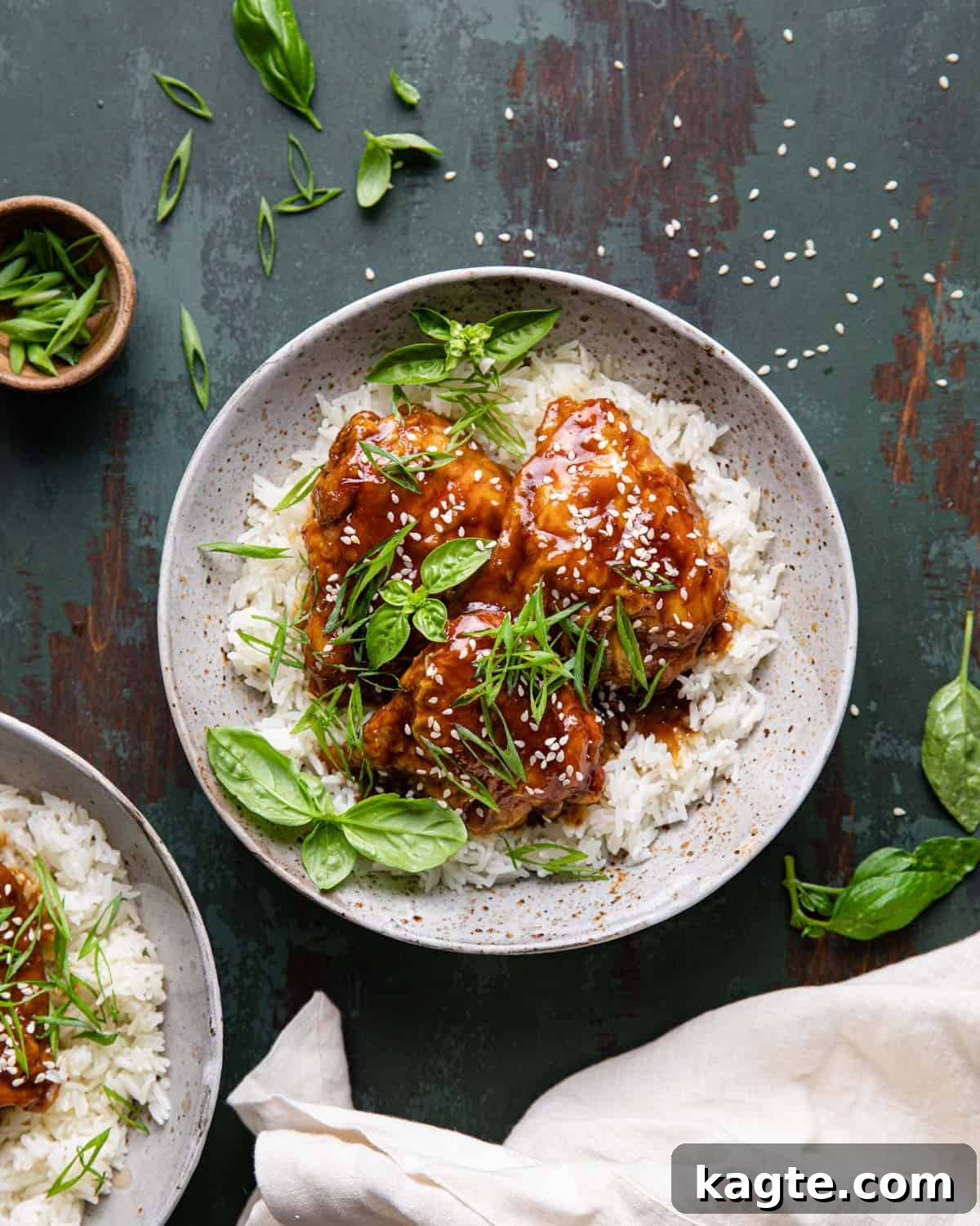 Easy Air Fryer Teriyaki Chicken 2 Air fryer teriyaki chicken over a bed or rice. Golden-brown crispy chicken thighs drizzled with a rich teriyaki glaze, served on a bed of white rice, garnished with green onions.