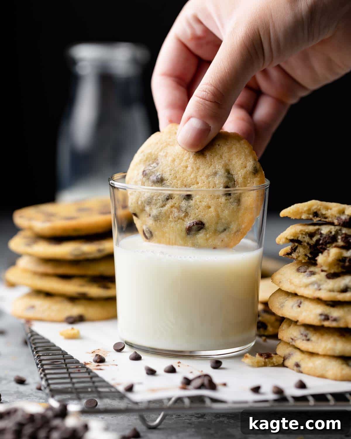 Freshly baked chocolate chip cookie being dunked into a glass of cold milk, highlighting its soft texture and melted chocolate chips.