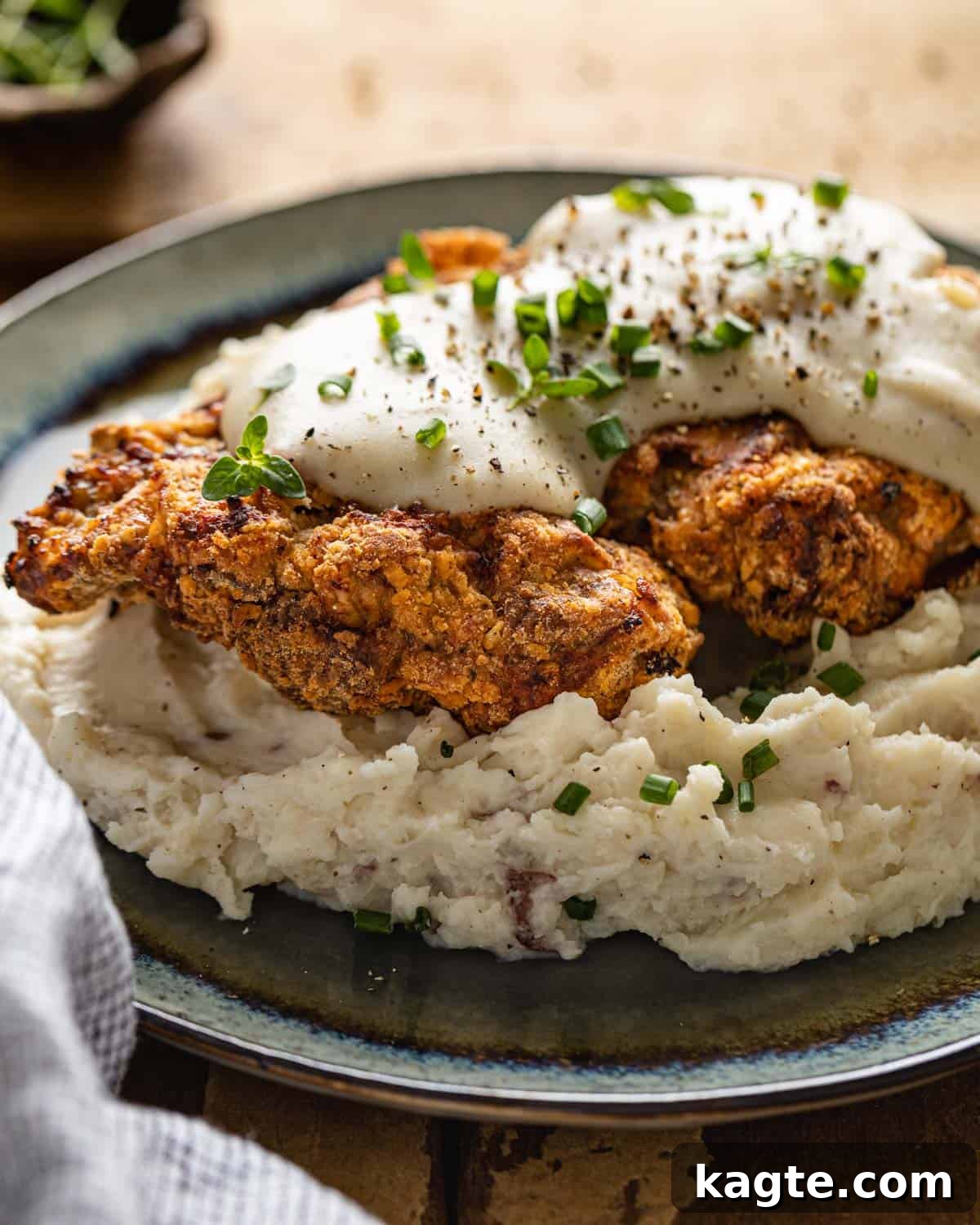 Crispy Air Fryer Chicken Fried Steak 10 A perfectly air-fried chicken fried steak, covered in creamy white gravy, served on a rustic blue plate.
