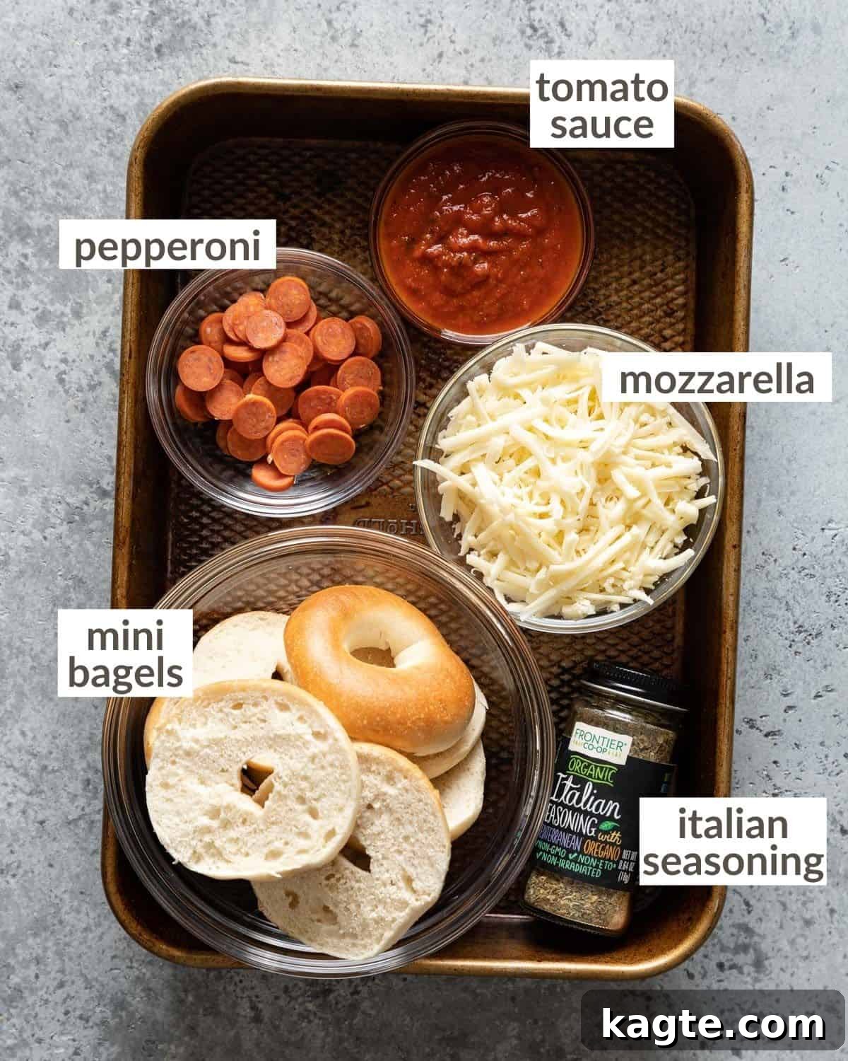 Crispy Air Fryer Bagel Bites Frozen and Fresh 3 Overhead shot of all individual ingredients for air fryer bagel bites laid out in small bowls, including mini bagels, shredded mozzarella cheese, mini pepperonis, and pizza sauce, ready for assembly.