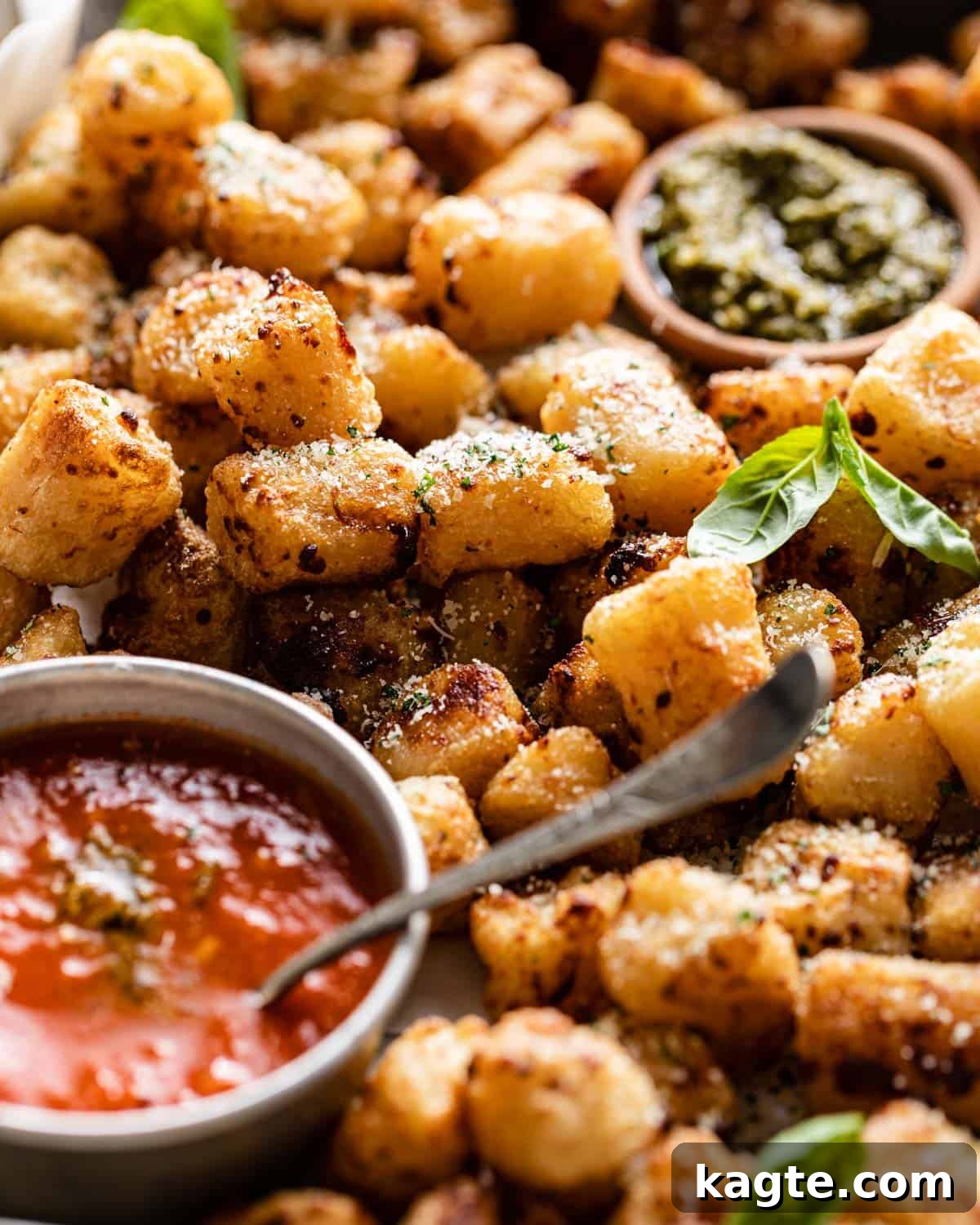 A close-up of crispy, air-fried Trader Joe's cauliflower gnocchi piled high in a rustic bowl, ready to be served, with a hint of dipping sauce in the background.